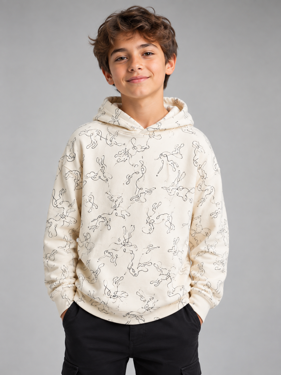   Nutmeg Boys Printed Hoodie in UK Size 12–13 Years. Cream hoodie with playful all-over doodle print, comfortable fit and casual everyday style.